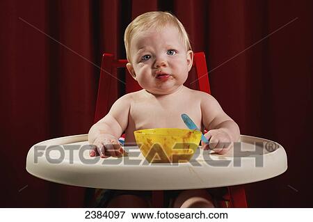 Stock Photo - A young boy sits in his highchair eating a meal; Alberta, Canada. Fotosearch