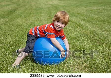 A young boy with red hair plays with a large blue ball on the grass; Stony Plain, Alberta, Canada View Large Photo Image Stock Photo - A young boy with red hair plays with a large blue ball on the grass; Stony Plain, Alberta, Canada. Fotosearch