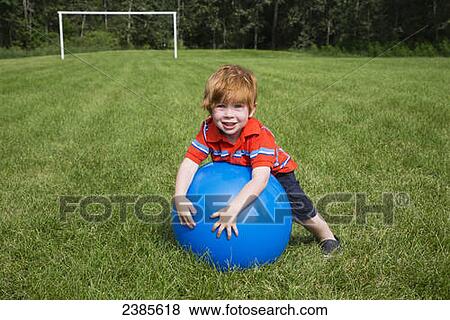 A young boy with red hair plays with a large blue ball on the grass; Stony Plain, Alberta, Canada View Large Photo Image Stock Photo - A young boy with red hair plays with a large blue ball on the grass; Stony Plain, Alberta, Canada. Fotosearch
