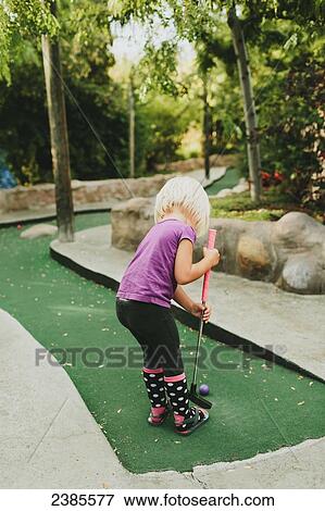 Stock Photo - A young girl playing miniature golf; Peachland, British Columbia, Canada. Fotosearch