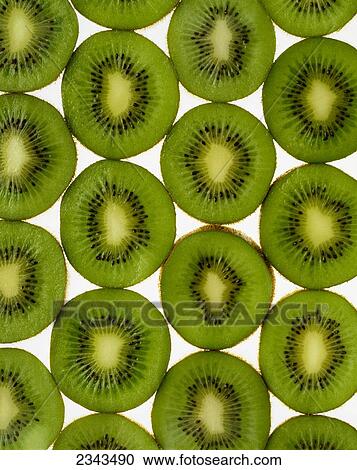 Stock Image - Agriculture - Kiwi slices arranged in rows and backlit, studio. Version 2.. Fotosearch