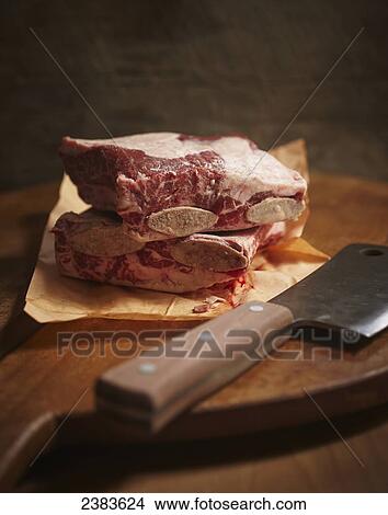 Picture - Beef short ribs and cleaver on cutting board. Fotosearch