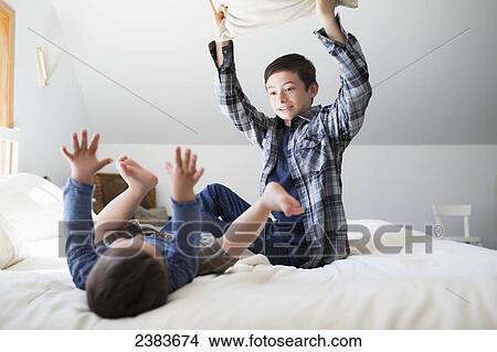 Brothers having a pillow fight on a bed at home; Victoria, British Columbia, Canada View Large Photo Image Picture - Brothers having a pillow fight on a bed at home; Victoria, British Columbia, Canada. Fotosearch