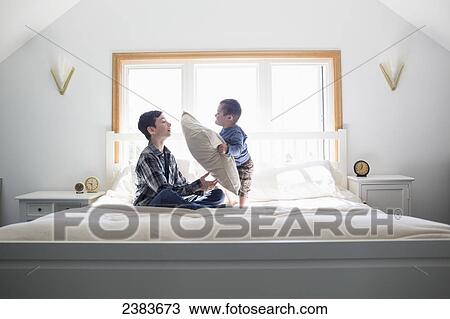 Brothers playing with a pillow on a big bed at home; Victoria, British Columbia, Canada View Large Photo Image Stock Image - Brothers playing with a pillow on a big bed at home; Victoria, British Columbia, Canada. Fotosearch