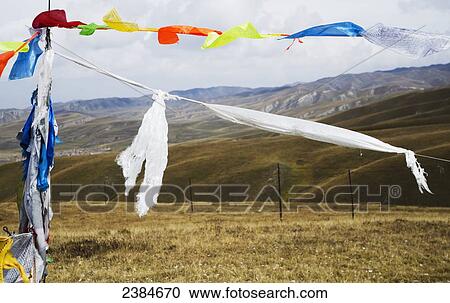 Stock Image - Colourful prayer flags with the tibetan mountains in the distance; Tibet, China. Fotosearch