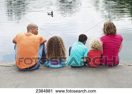 Family of five sitting on the edge of a pond; Menlo Park, California, United States of America View Large Photo Image Stock Image - Family of five sitting on the edge of a pond; Menlo Park, California, United States of America. Fotosearch