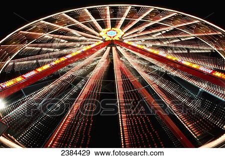 Stock Photo - Ferris wheel glowing and spinning at nighttime; Locarno, Ticino, Switzerland. Fotosearch