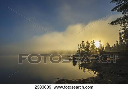 Fog over a lake at sunrise; Quebec, Canada View Large Photo Image Stock Photo - Fog over a lake at sunrise; Quebec, Canada. Fotosearch
