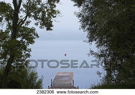 Stock Photograph - Foggy morning at the lake; Waterloo, Quebec, Canada. Fotosearch