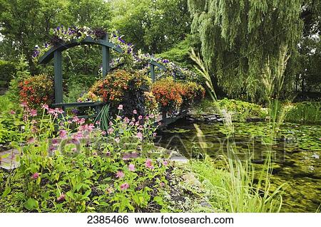 Footbridge With Hanging Baskets Over A Pond In Summer Centre De