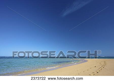 Stock Image - Footprints in the sand along the water's edge of Tunnels Beach; Kauai, Hawaii, United States of America. Fotosearch