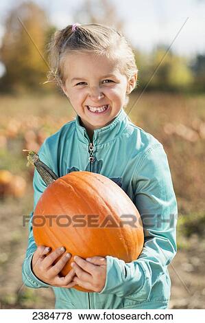 Girl holding a pumpkin in a pumpkin patch with a big smile; Trenton, Ontario, Canada View Large Photo Image Stock Photo - Girl holding a pumpkin in a pumpkin patch with a big smile; Trenton, Ontario, Canada. Fotosearch