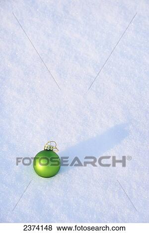 Stock Photo - Green Christmas ornament in the snow; St. Albert, Alberta, Canada. Fotosearch