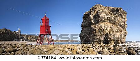 Picture - Groyne lighthouse beside a rock formation along the shoreline; South Shields, Tyne and Wear, England. Fotosearch