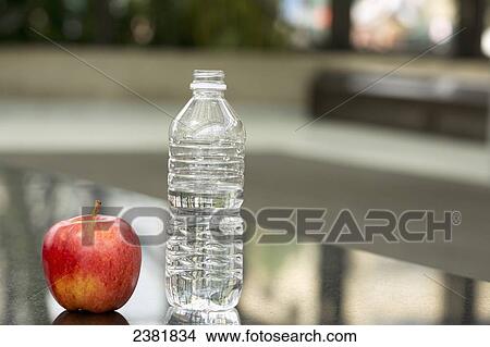Picture - Healthy Snack Of Bottled Water And Apple In Business Environment; Edmonton, Alberta, Canada. Fotosearch