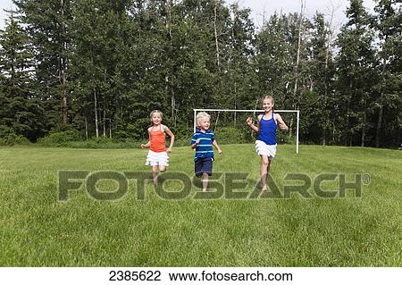 Kids running across a grass field in a park; Stony Plain, Alberta, Canada View Large Photo Image Stock Image - Kids running across a grass field in a park; Stony Plain, Alberta, Canada. Fotosearch