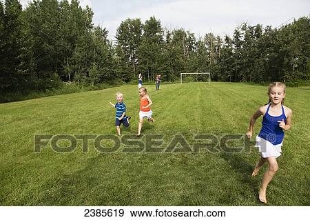 Kids running across a grass field in a park with the parents in the background; Stony Plain, Alberta, Canada View Large Photo Image Stock Photo - Kids running across a grass field in a park with the parents in the background; Stony Plain, Alberta, Canada. Fotosearch