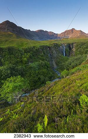 Stock Image - Looking up river to the Eas Mor waterfall and the hills of the Black Cuillin at dusk; Isle of Skye, Scotland. Fotosearch
