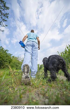 Stock Image - Low angle view of a woman walking her dog; Locarno, Ticino, Switzerland. Fotosearch