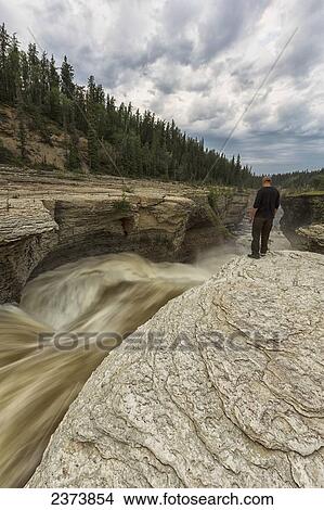 Man watches the Trout River flowing over Whittaker Falls along the Mackenzie Highway; Northwest Territories, Canada View Large Photo Image Picture - Man watches the Trout River flowing over Whittaker Falls along the Mackenzie Highway; Northwest Territories, Canada. Fotosearch