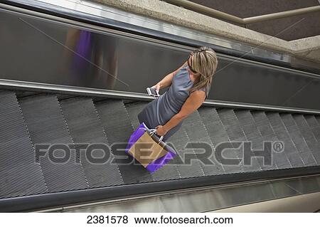 Mature Businesswoman Checking Cell Phone While Shopping Using Escalator; Edmonton, Alberta, Canada View Large Photo Image Stock Photo - Mature Businesswoman Checking Cell Phone While Shopping Using Escalator; Edmonton, Alberta, Canada. Fotosearch