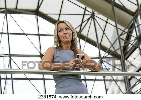 Mature Professional Businesswoman In Downtown Office Environment Using Cell Phone; Edmonton, Alberta, Canada View Large Photo Image Picture - Mature Professional Businesswoman In Downtown Office Environment Using Cell Phone; Edmonton, Alberta, Canada. Fotosearch