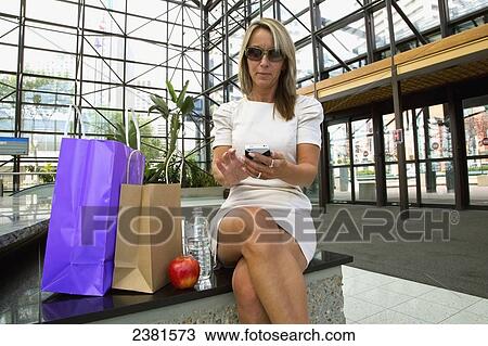 Mature Professional Businesswoman In Downtown Office Environment Using A Cell Phone And Eating A Healthy Snack While Shopping And Taking A Snack Break; Edmonton, Alberta, Canada View Large Photo Image Stock Image - Mature Professional Businesswoman In Downtown Office Environment Using A Cell Phone And Eating A Healthy Snack While Shopping And Taking A Snack Break; Edmonton, Alberta, Canada. Fotosearch