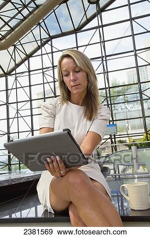 Mature Professional Businesswoman In Downtown Office Environment Using A Mobile Tablet Device; Edmonton, Alberta, Canada View Large Photo Image Stock Photo - Mature Professional Businesswoman In Downtown Office Environment Using A Mobile Tablet Device; Edmonton, Alberta, Canada. Fotosearch