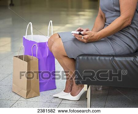 Mature Professional Businesswoman Pausing To Make A Phone Call On Cell Phone While Shopping; Edmonton, Alberta, Canada View Large Photo Image Stock Image - Mature Professional Businesswoman Pausing To Make A Phone Call On Cell Phone While Shopping; Edmonton, Alberta, Canada. Fotosearch