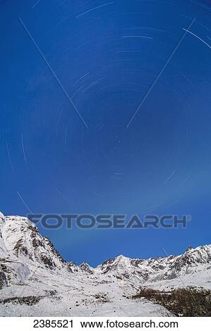 Stock Image - Northern lights and star trails in the sky above the now covered Talkeetna mountains, Hatchers Pass State Recreation Area; Alaska, United States of America. Fotosearch
