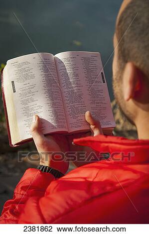 Stock Image - Over shoulder image of man reading Bible; Starkville, Mississippi, United States of America. Fotosearch