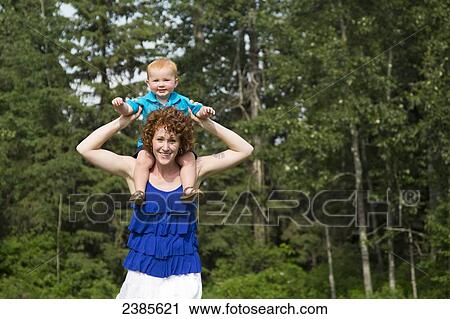 Stock Image - Portrait of a mother holding her young son on her shoulders; Stony Plain, Alberta, Canada. Fotosearch