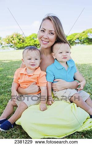 Stock Photo - Portrait of a mother with young twin sons; Honolulu, Oahu, Hawaii, United States of America. Fotosearch
