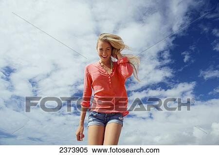 Stock Photography - Portrait of a teenage girl with long blond hair against a blue sky and cloud; Kauai, Hawaii, United States of America. Fotosearch