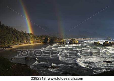 Stock Photo - Rainbows seen through storm clouds over Crescent Beach; Cannon Beach, Oregon, United States of America. Fotosearch