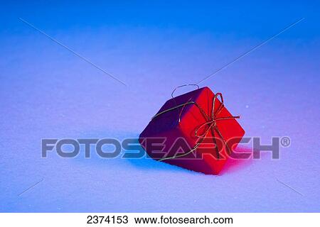 Stock Image - Red Christmas present in the snow; St. Albert, Alberta, Canada. Fotosearch