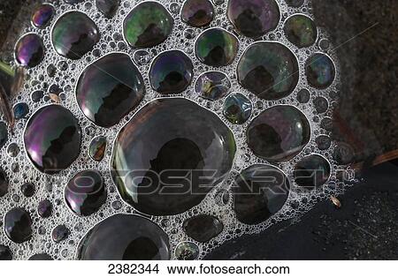 Picture - Sea foam creates colourful patterns and reflections; Cannon Beach, Oregon, United States of America. Fotosearch