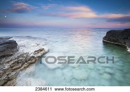 Stock Image - Seeing into the clear rocky water at sunset at Cave Point in Sturgeon Bay; Wisconsin, United States of America. Fotosearch