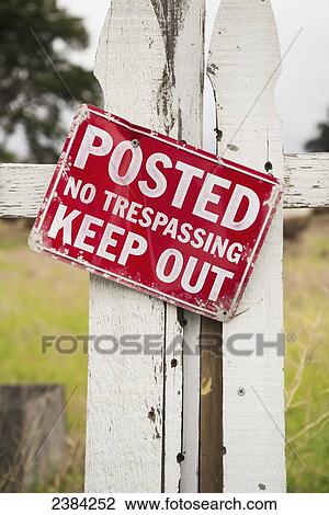 Stock Image - Sign on an old white picket fence saying Posted Keep Out No Trespassing; Monterey Bay, California, United States of America. Fotosearch