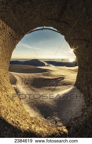 Sunrise through a circle of cement on the cold winter shores of Lake Michigan; Wisconsin, United States of America View Large Photo Image Stock Photo - Sunrise through a circle of cement on the cold winter shores of Lake Michigan; Wisconsin, United States of America. Fotosearch