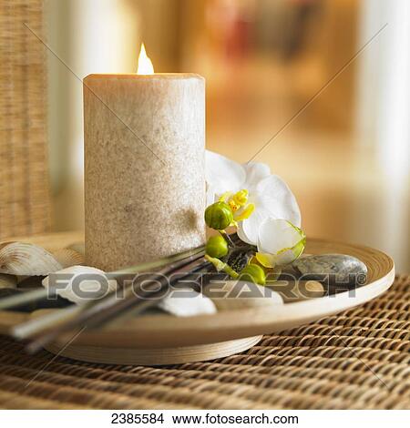 Picture - Taupe pillar candle on bamboo plate with shells and white orchid; Victoria British Columbia, Canada. Fotosearch