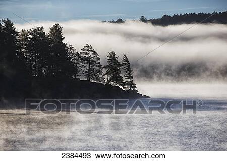 The mist rises off the Lake of Two Rivers at sunrise, Algonquin Park; Ontario, Canada View Large Photo Image Stock Image - The mist rises off the Lake of Two Rivers at sunrise, Algonquin Park; Ontario, Canada. Fotosearch