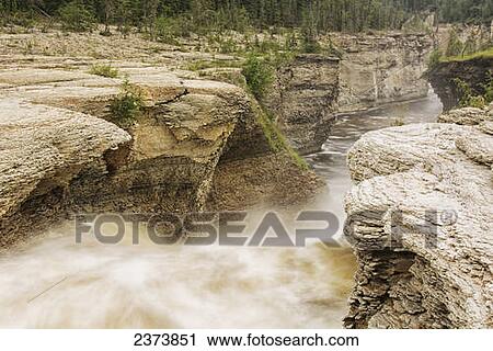 Stock Image - The Trout River flows over whittaker Falls; Northwest Territories, Canada. Fotosearch