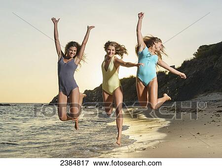 Three young women in bathing suits jumping in mid-air together on the beach; Tarifa, Cadiz, Andalusia, Spain View Large Photo Image Stock Photo - Three young women in bathing suits jumping in mid-air together on the beach; Tarifa, Cadiz, Andalusia, Spain. Fotosearch