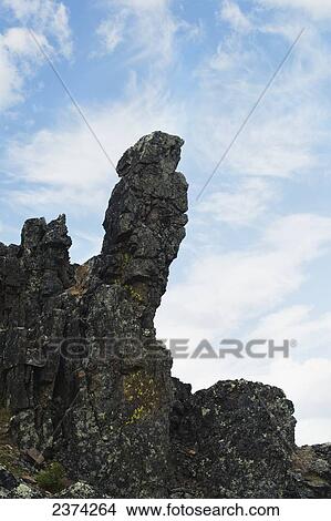 Picture - Unique rock formation against blue sky and cloud; Yukon, Canada. Fotosearch
