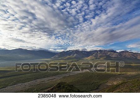 Stock Photo - View of dramatic clouds over Polychrome Pass at sunrise, Denali National Park; Alaska, United States of America. Fotosearch