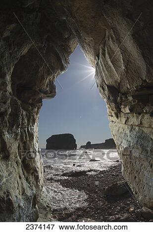 View of rock formations and the coastline through a natural rock arch; South Shields, Tyne and Wear, England View Large Photo Image Stock Photo - View of rock formations and the coastline through a natural rock arch; South Shields, Tyne and Wear, England. Fotosearch