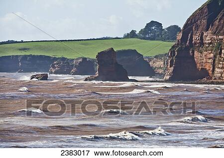 Stock Photo - Waves and rough waters along the rugged coastline; Ladram Bay, South Devon, England. Fotosearch