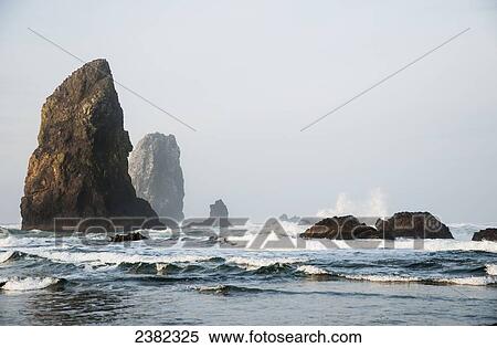 Stock Photography - Waves break around the stone needles; Cannon Beach, Oregon, United States of America. Fotosearch