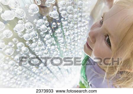 Stock Image - Young girl looking at crystals in window display of the Dubai Mall; Dubai, United Arab Emirates. Fotosearch